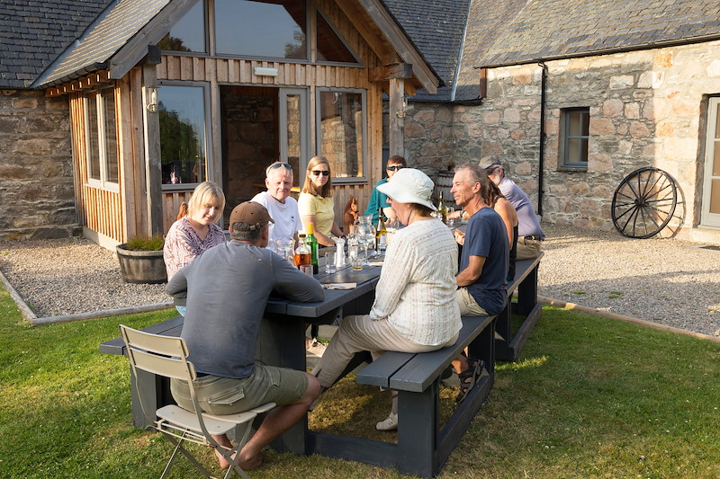 Group from travel company, Wilderness Scotland, eating dinner outside Ballintean Mountain Lodge, Glenfeshie, Cairngorms, Scotland.