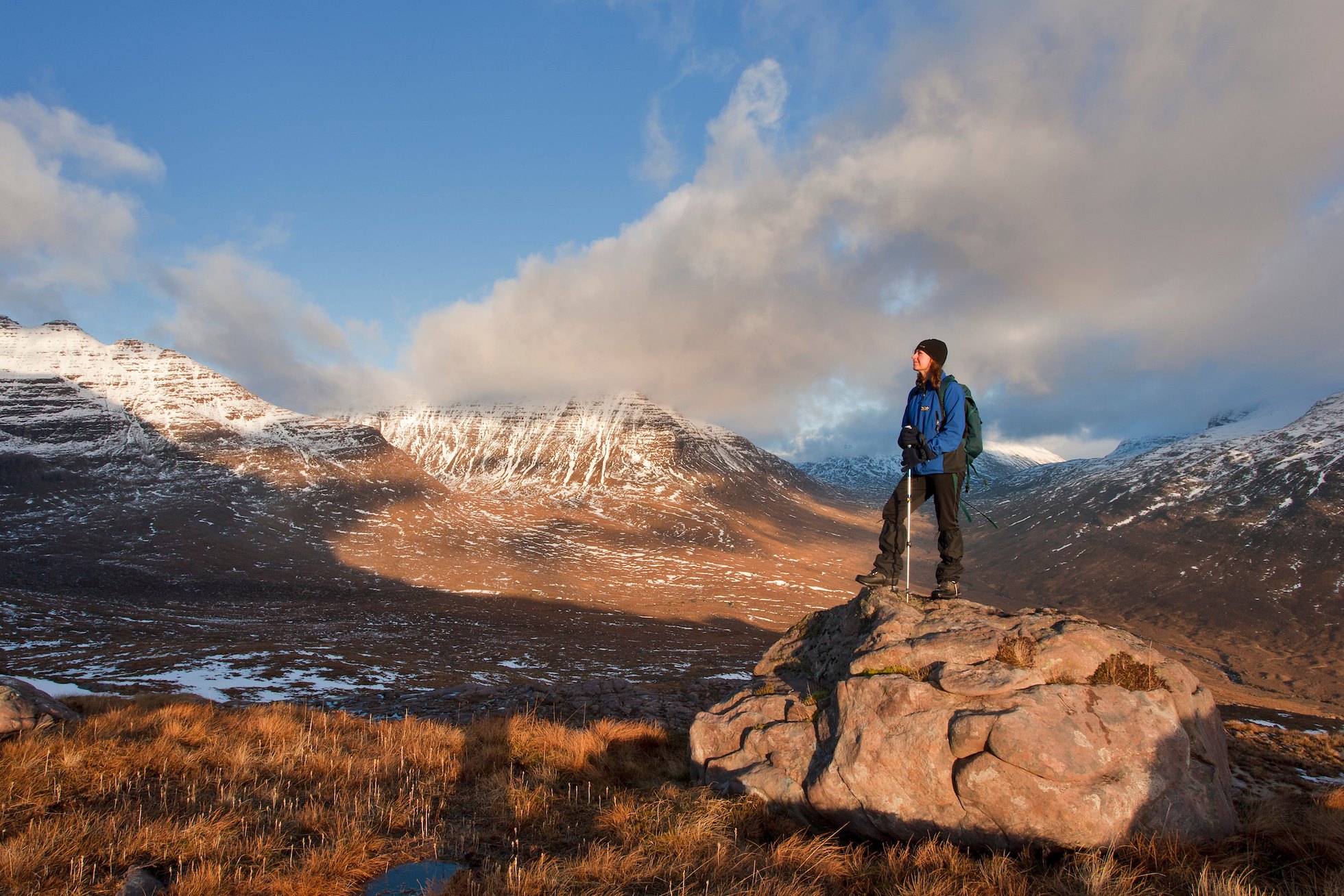 Woman (aged 40) on rock admiring the view on the route up Tom na Gruagaich, Beinn Alligin, Torridon, Scotland