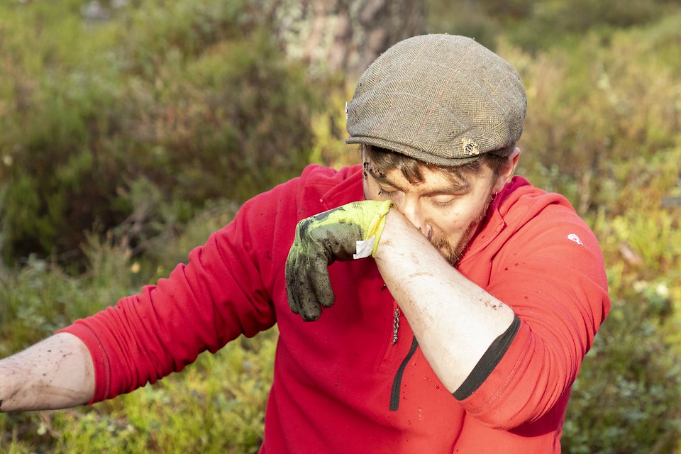 Close-up of man wiping mud from face during a habitat restoration volunteer day, Anagach Woods, Cairngorms National Park, February 2025