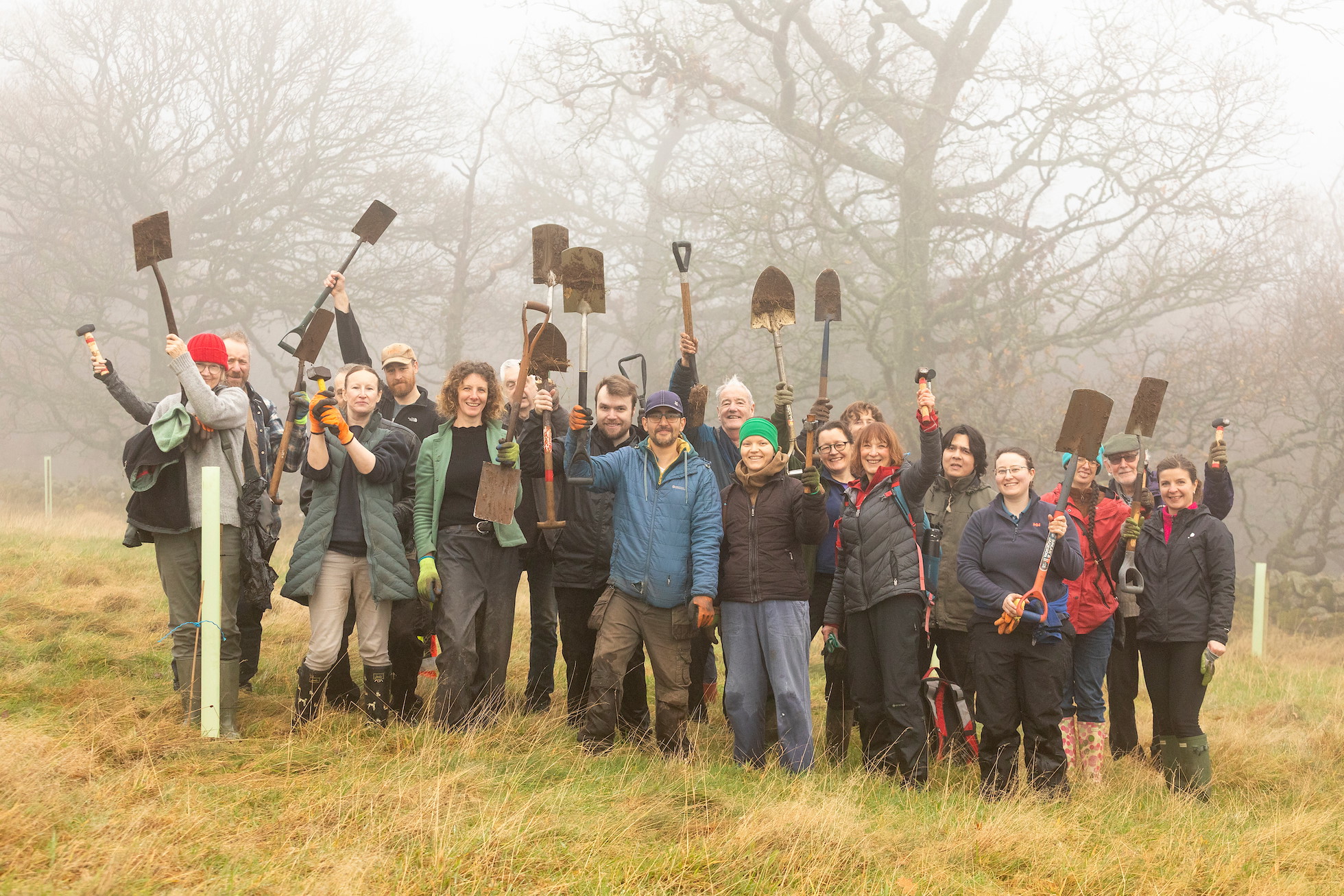 Group photograph of volunteers holding spades in the air at a tree planting event at Sauchie Home Farm, Stirling, Scotland, December 2025